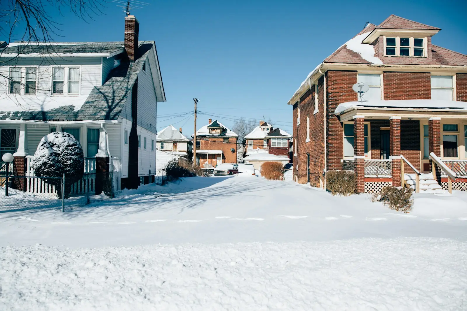 Snow-covered street lined with older brick and wood-sided houses